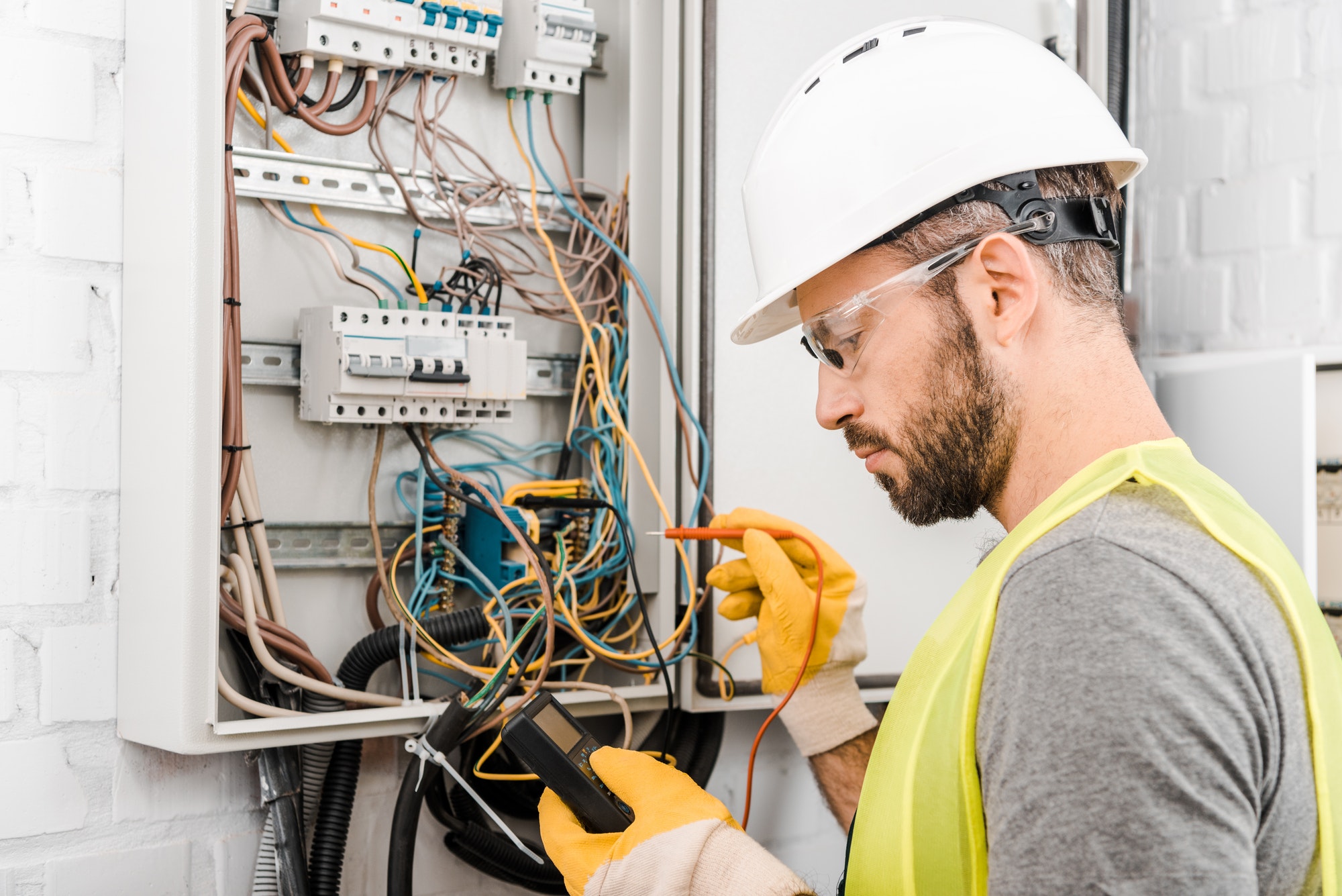 handsome-electrician-checking-electrical-box-with-multimetr-in-corridor.jpg